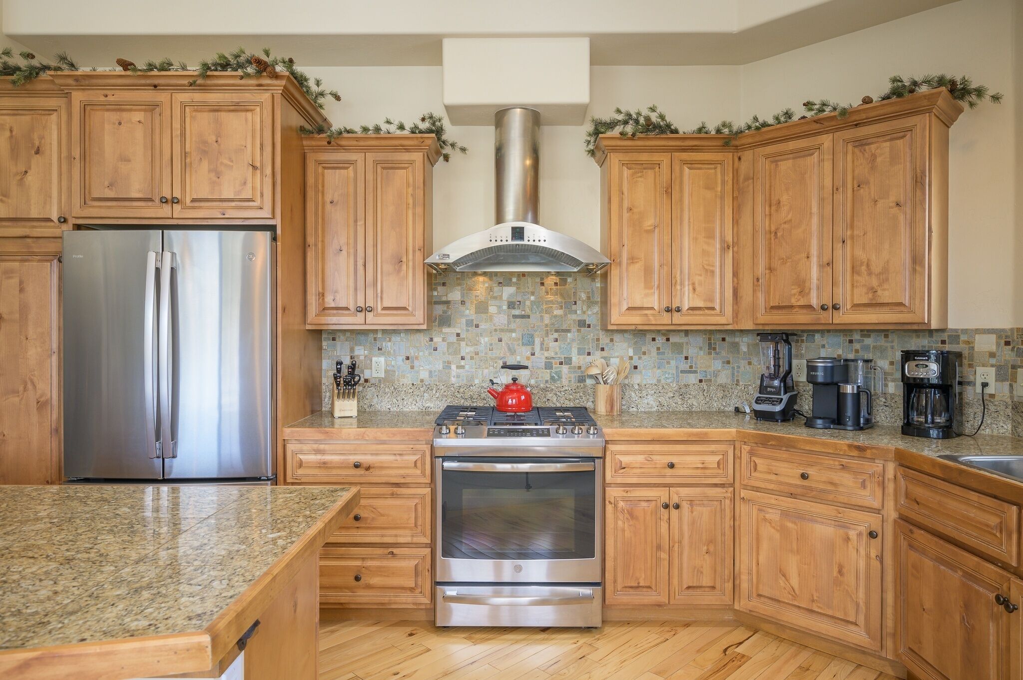 A kitchen with wooden cabinets, a stainless steel refrigerator, a gas stove, and a built-in oven.