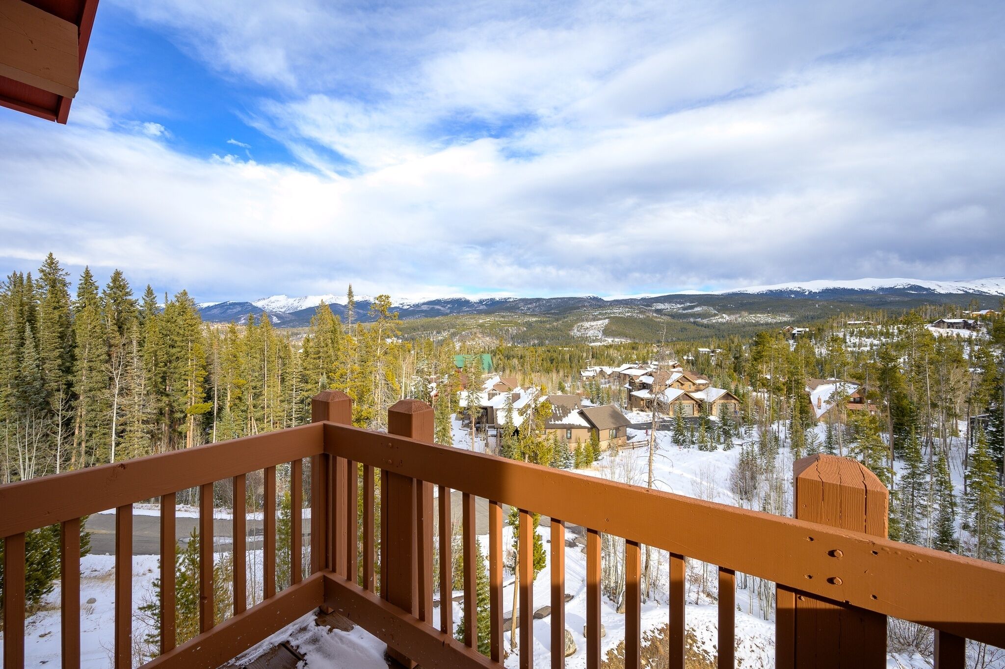 A snowy mountain landscape with a wooden balcony railing.