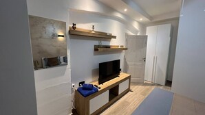 A modern living room with a flat-screen TV on a wooden console, a ceiling fan, and built-in shelves above the TV.