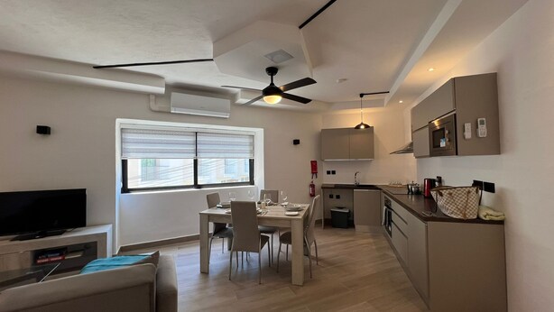 A modern apartment with a dining area, kitchen, and living space.