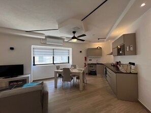 A modern apartment with a dining area, kitchen, and living space. - Portobello Central Suite (Sliema)