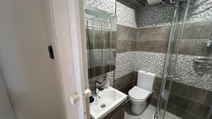 A modern bathroom with a glass shower enclosure, a white sink, and a toilet.