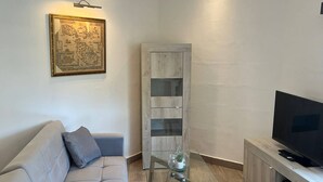 A modern living room with a sofa, a glass coffee table, a TV, and a wooden cabinet.