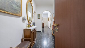 Un couloir avec un banc en bois, un miroir et une porte dotée d’une poignée ronde.