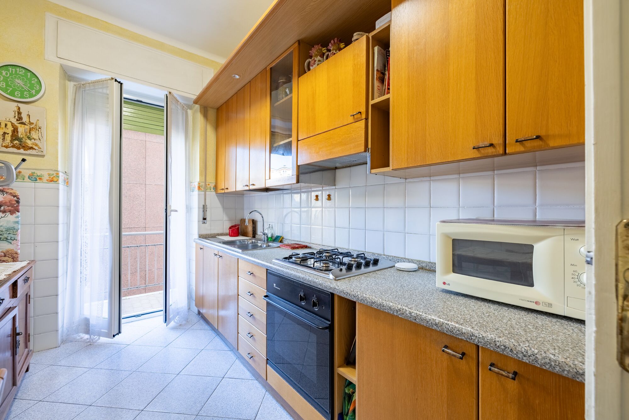 A kitchen with wooden cabinets, a gas stove, a microwave, and a sink.