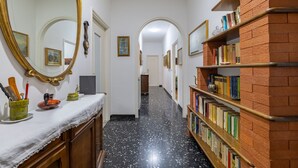 Un couloir doté d’un sol en marbre, de bibliothèques, d’un miroir et de tableaux encadrés accrochés aux murs.