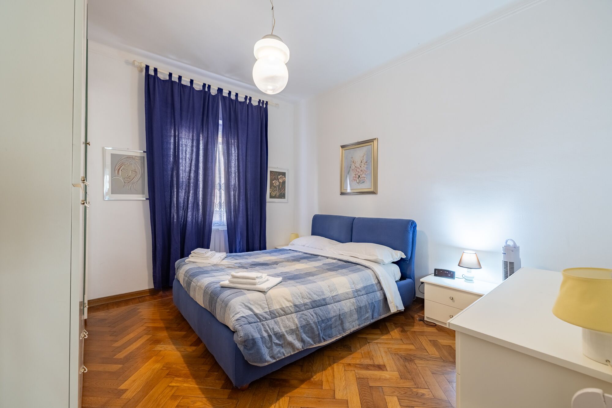 A bedroom with a bed, a bedside table, a lamp, and a picture on the wall.