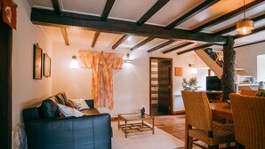 Ein gemütliches Wohnzimmer mit einer Ledersofa, einem Holztisch und Korbstühlen.
