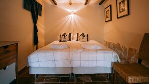 Ein Schlafzimmer mit einem großen Bett, einer hölzernen Bank und einer Steinwand.