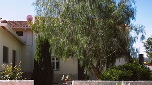 Un edificio con un muro de piedra, un árbol y una antena parabólica.