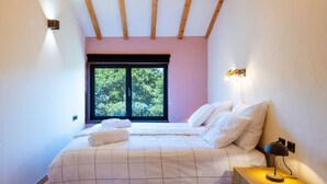 A bedroom with a bed, a nightstand, a lamp, a window, and a ceiling light. - Casa Pinhal – Stylish Apartment with Valley and Pine Forest Views (Carvalhal Benfeito)