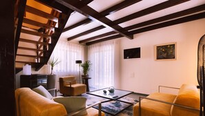 A modern living room with a staircase, two yellow sofas, a glass coffee table, and a painting on the wall. - Casa Pinhal – Stylish Apartment with Valley and Pine Forest Views (Carvalhal Benfeito)