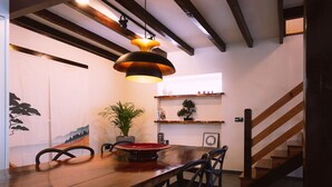 A wooden dining table with chairs, a potted plant, and a wall with a painting. - Casa Pinhal – Stylish Apartment with Valley and Pine Forest Views (Carvalhal Benfeito)