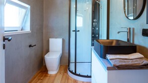 A modern bathroom with a glass-enclosed shower, a white toilet, and a black sink with a mirror above it. - Casa Pinhal – Stylish Apartment with Valley and Pine Forest Views (Carvalhal Benfeito)