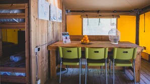 Un comedor de madera con una mesa, cuatro sillas verdes, un florero y una ventana con vistas.