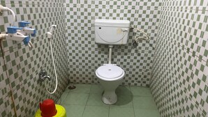 A small bathroom with a toilet, a sink, and a yellow fire extinguisher. - Hotel Miracle Stay (Bhubaneshwar)