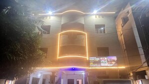 A hotel entrance with a neon sign, a guest house, and a display screen advertising rooms. - Hotel Miracle Stay (Bhubaneshwar)