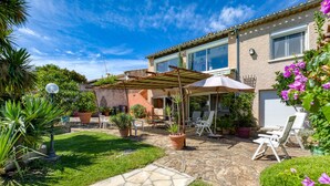 A house with a patio, outdoor furniture, and potted plants.