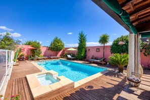 En træterrasse med swimmingpool, liggestole og jacuzzi.