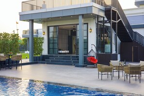 Une maison moderne dotée d’une piscine, d’un espace de détente extérieur et d’un escalier.