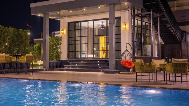Un hotel moderno con piscina, asientos al aire libre y una escalera que lleva al nivel superior.