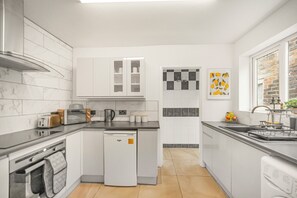 Una cocina moderna con alacenas blancas, lavavajillas, tostadora y cafetera.