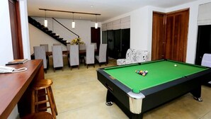 A pool table in a room with a bar, chairs, and a staircase. - The Essence (Nuwara Eliya)