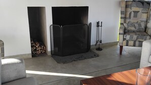 A living room with a fireplace, a sofa, a coffee table, and a patterned armchair. - The Essence (Nuwara Eliya)