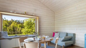 A cozy cabin interior with a dining table, seating area, and a large window offering a view of a forest. - Time Out in Argental – Holiday Home Hagg near Lake Constance (Neukirch)