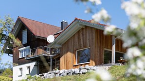 A wooden house with a satellite dish, a balcony, and a stone wall. - Time Out in Argental – Holiday Home Hagg near Lake Constance (Neukirch)