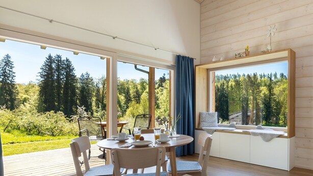 A room with a dining table, chairs, a window seat, and a view of a forest. - Time Out in Argental – Holiday Home Hagg near Lake Constance (Neukirch)