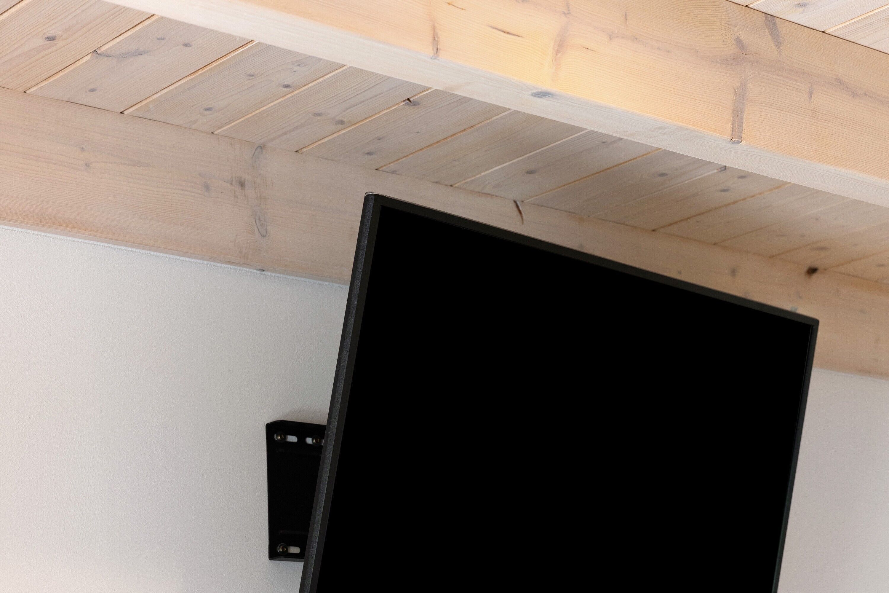 Ein Zimmer mit Holzboden, einem schwarzen Lautsprecher und einer weißen Wand.