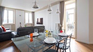 A modern living room with a glass dining table, leather sofa, and a view of the outdoors. - Apartment 'La Gioconda' with Lake View, Wi-Fi and Air Conditioning (Salò)
