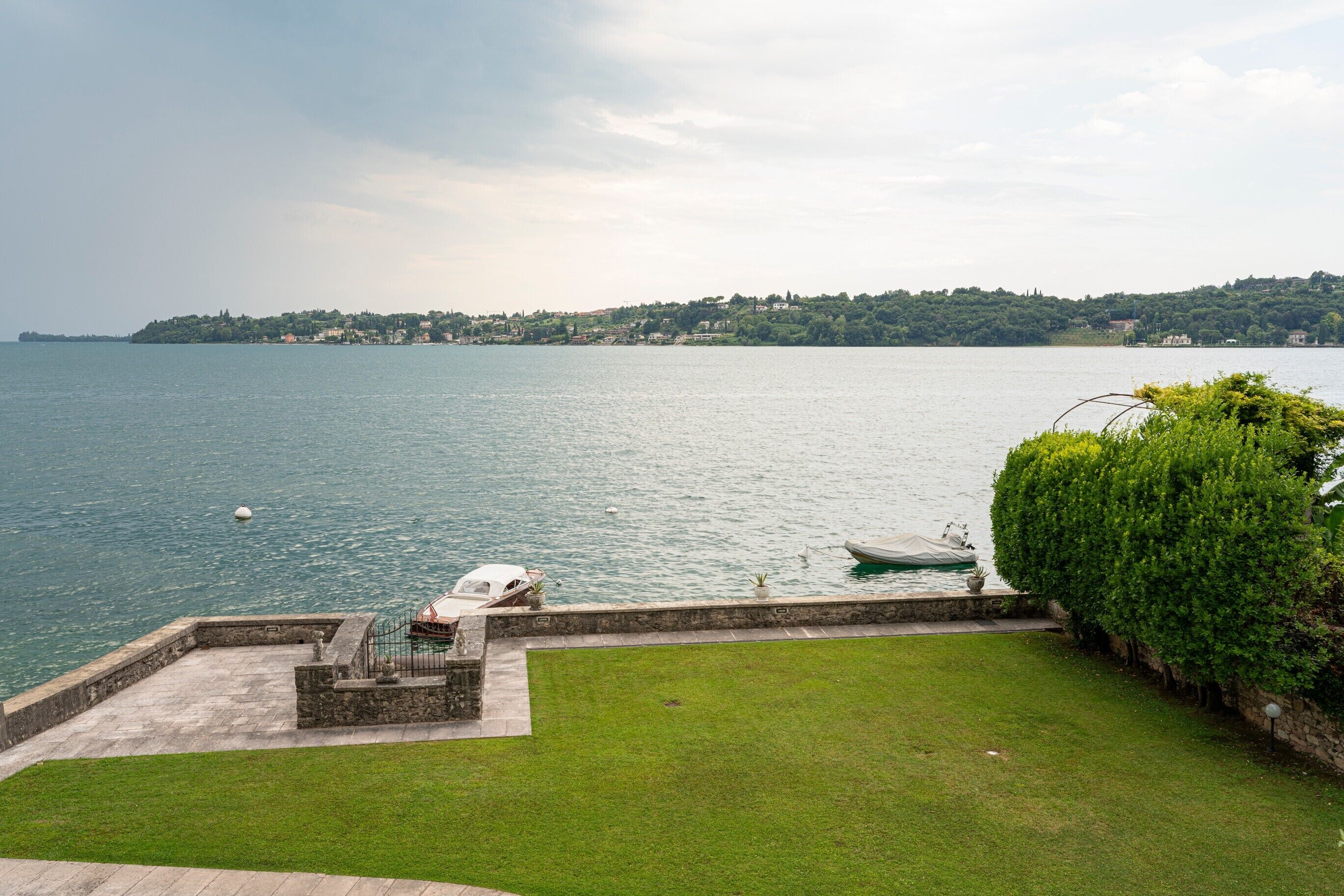 A waterfront property with a grassy lawn, a dock, and a view of a distant hill with buildings.