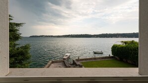 A view of a lake with boats, a grassy area, and a distant shoreline. - Apartment 'La Gioconda' with Lake View, Wi-Fi and Air Conditioning (Salò)