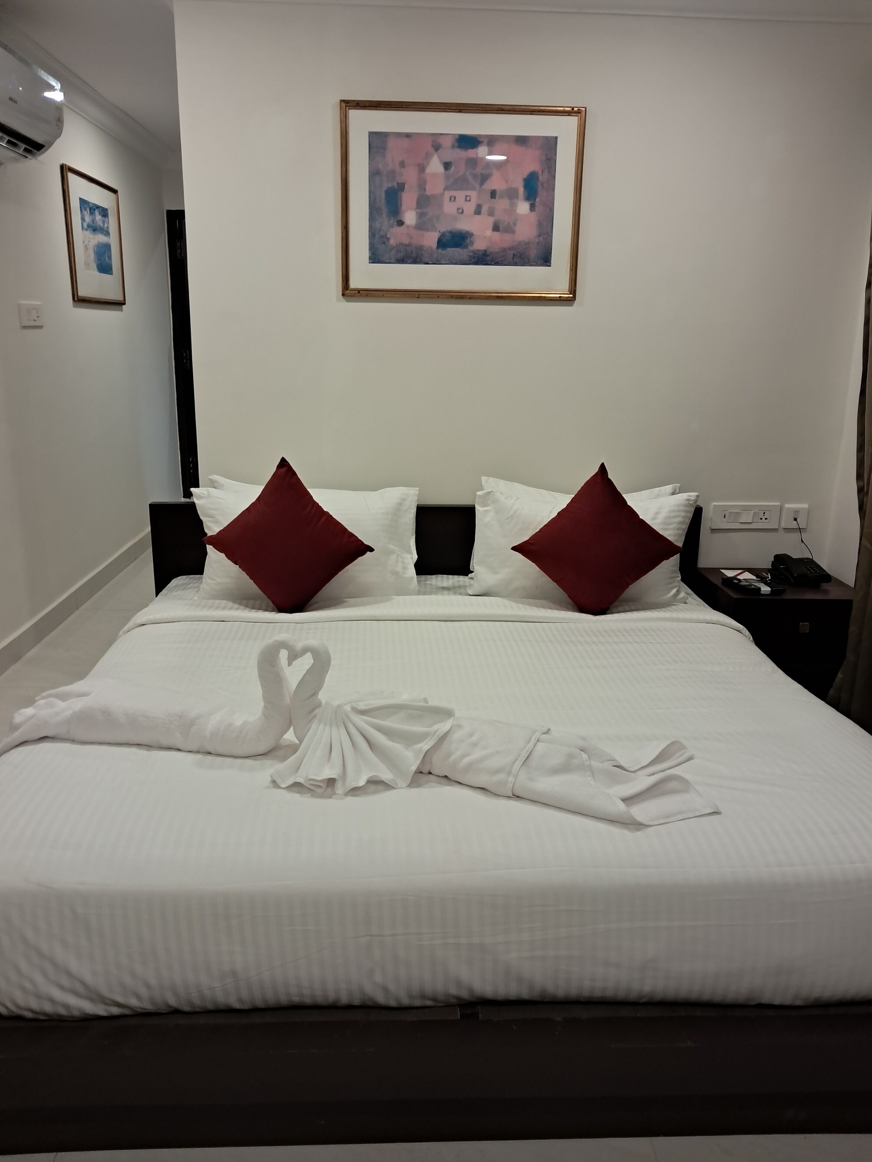 Una camera d'albergo con un letto rifatto, un quadro appeso al muro e un telefono sul comodino.