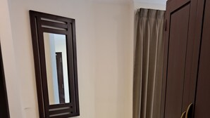 Una habitación con un armario de madera oscura, un espejo en la pared y una cortina.