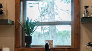 A kitchen with a wooden-framed window, a black faucet, a potted plant, and a sign that reads "Goods Only". - Seduction Awaits – Bold, Romantic Escape for Adventurous Couples (Sevierville)