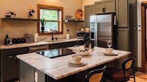 A modern kitchen with a central island, bar stools, a refrigerator, and a microwave. - Seduction Awaits – Bold, Romantic Escape for Adventurous Couples (Sevierville)