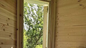 Une pièce de cabane en bois avec une porte donnant sur un espace extérieur verdoyant.