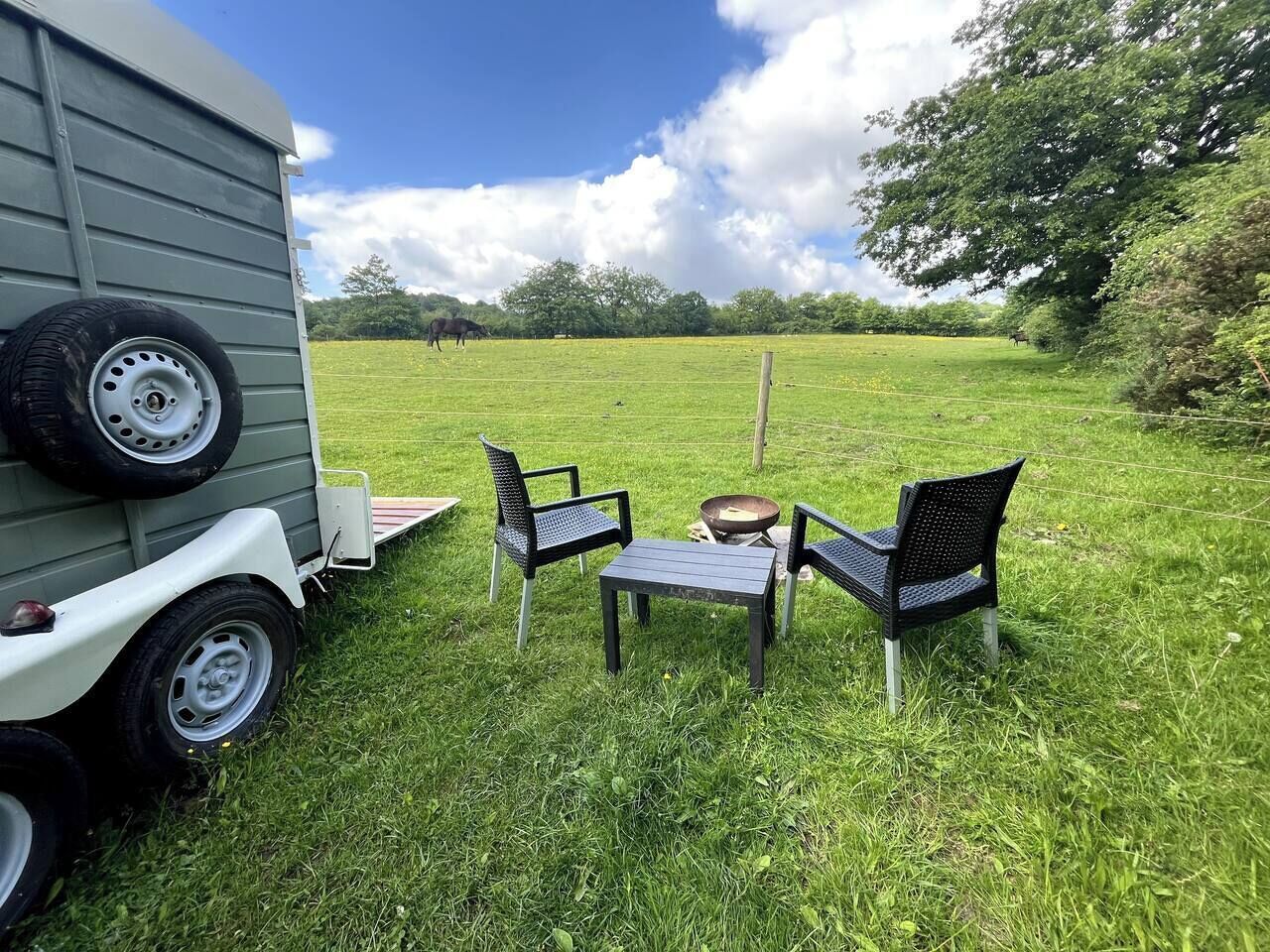 A trailer with a table and chairs in a grassy field.