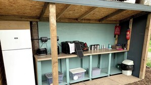 Un espace cuisine compact comprenant un réfrigérateur, une machine à café et des étagères de rangement.