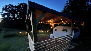 A small, wooden structure with a bench and a table, surrounded by string lights. - The Pig Sty - Farm Stay (Shepshed)
