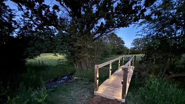 A wooden bridge over a small stream in a wooded area. - The Pig Sty - Farm Stay (Shepshed)