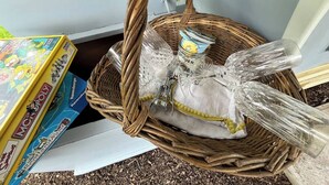 A wicker basket with glass bottles and a Monopoly game box. - The Pig Sty - Farm Stay (Shepshed)