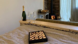 A cozy room with a chessboard, a bottle of champagne, and glasses on a wooden table. - The Barn - Farm Stay (Shepshed)