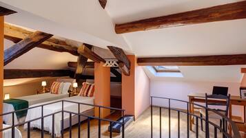 Une chambre à coucher aménagée dans un espace de type « loft », avec des poutres en bois apparentes, une lucarne, un bureau et une chaise.