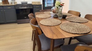 Ein Essbereich mit einem Holztisch, gewobenen Platzsets und Stühlen.