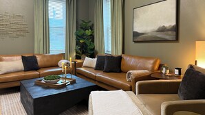 Ein modernes Wohnzimmer mit einer braunen Ledersofa, einem Couchtisch und einem großen Gemälde an der Wand.