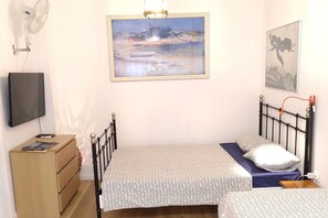 Une chambre à coucher comprenant un lit, une commode, un téléviseur et deux œuvres d’art encadrées.